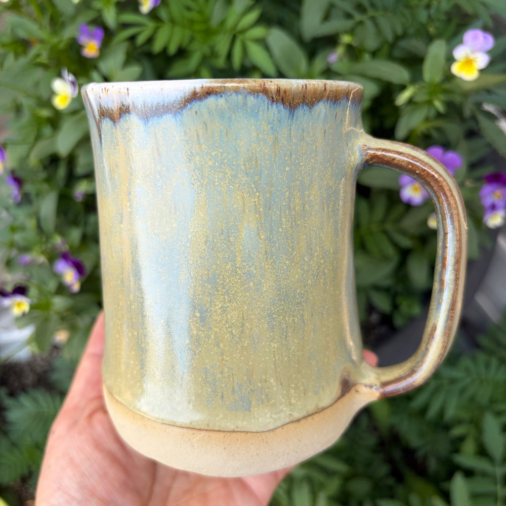 Handmade ceramic mug with brown drips and iridescent effects of gold and blue.